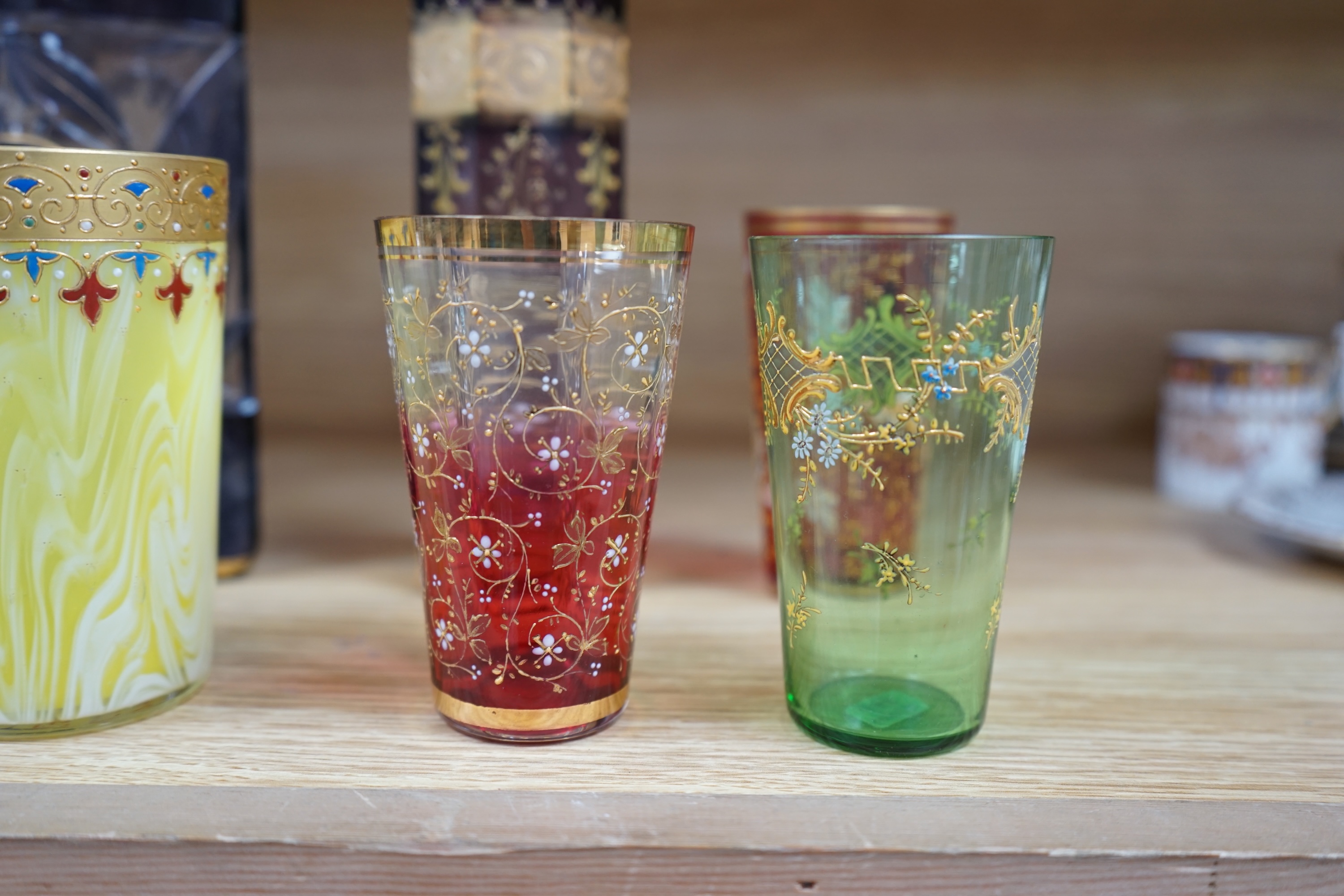 Nine Bohemian decorated glass items including a gilt rimmed and decorated glass inscribed ‘Moser 1503 D553/a’, four smaller glasses, a pair of tall stemmed glasses, 22.5cm, and two vases, tallest 19.5cm. Condition - good